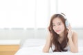 Beautiful asian young woman enjoy listen music with headphone while lying in bedroom Royalty Free Stock Photo