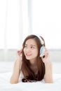 Beautiful asian young woman enjoy listen music with headphone while lying in bedroom. Royalty Free Stock Photo