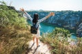 Beautiful Asian young woman enjoying freedom and open hands in rocks mountain with lake and tree.