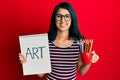 Beautiful asian young woman holding art notebook and colored pencils smiling with a happy and cool smile on face Royalty Free Stock Photo