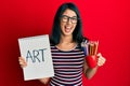 Beautiful asian young woman holding art notebook and colored pencils winking looking at the camera with sexy expression, cheerful Royalty Free Stock Photo