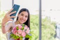 Beautiful asian young woman holding bouquet and smiling with taking a selfie by smartphone Royalty Free Stock Photo