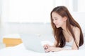 Beautiful asian young woman lying on bed using laptop at bedroom Royalty Free Stock Photo