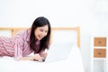 Beautiful asian young woman lying on bed using laptop at bedroom Royalty Free Stock Photo