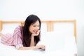 Beautiful asian young woman lying on bed using laptop at bedroom for leisure and relax Royalty Free Stock Photo