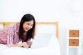 Beautiful asian young woman lying on bed using laptop at bedroom Royalty Free Stock Photo