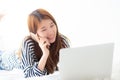 Beautiful asian young woman lying on bed using laptop and talking mobile smart phone at bedroom for leisure and relax, freelance Royalty Free Stock Photo