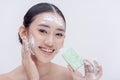Beautiful Asian young woman practicing proper hygiene by washing her face with a bar of facial soap. Royalty Free Stock Photo