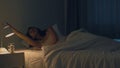 Beautiful Asian young woman sleeping cozily in her bedroom. Indian female hand turning off on light switch near bed in room at Royalty Free Stock Photo