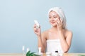 Beautiful Asian young woman smiling while applying white cream on her face with many packaging of facial cream and cosmetics on Royalty Free Stock Photo