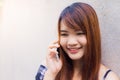 Beautiful asian young woman talking on mobile phone, over concrete wall. Vintage tone filter color style Royalty Free Stock Photo