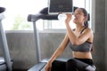 Beautiful Asian young woman tired taking a break from running or exercise sitting on treadmill machine drinking water  in fitness Royalty Free Stock Photo