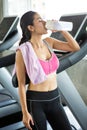 Beautiful Asian young woman tired taking a break from running or exercise standing on treadmill machine drinking water and towel Royalty Free Stock Photo