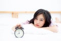 Beautiful asian young woman turn off alarm clock in morning, wake up for sleep with alarm clock, relax and lifestyle concept. Royalty Free Stock Photo