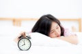 Beautiful asian young woman turn off alarm clock in morning, wake up for sleep with alarm clock, relax and lifestyle concept. Royalty Free Stock Photo