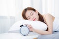 Beautiful asian young woman turn off alarm clock in morning, wake up for sleep with alarm clock. Royalty Free Stock Photo