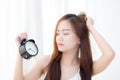 Beautiful asian young woman wake up in morning annoyed alarm clock holding hand. Royalty Free Stock Photo