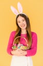 Beautiful asian young woman wear bunny ears standing smiling and holding basket with easter eggs Royalty Free Stock Photo