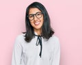 Beautiful asian young woman wearing business shirt and glasses looking positive and happy standing and smiling with a confident Royalty Free Stock Photo