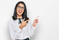 Beautiful asian young woman wearing business shirt and glasses smiling and looking at the camera pointing with two hands and Royalty Free Stock Photo