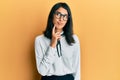 Beautiful asian young woman wearing business shirt thinking concentrated about doubt with finger on chin and looking up wondering Royalty Free Stock Photo