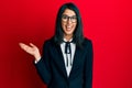 Beautiful asian young woman wearing business suit smiling cheerful presenting and pointing with palm of hand looking at the camera Royalty Free Stock Photo