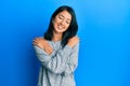Beautiful asian young woman wearing casual clothes hugging oneself happy and positive, smiling confident Royalty Free Stock Photo