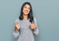 Beautiful asian young woman wearing casual clothes success sign doing positive gesture with hand, thumbs up smiling and happy Royalty Free Stock Photo