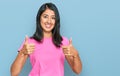 Beautiful asian young woman wearing casual pink t shirt approving doing positive gesture with hand, thumbs up smiling and happy Royalty Free Stock Photo