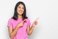 Beautiful asian young woman wearing casual pink t shirt smiling and looking at the camera pointing with two hands and fingers to Royalty Free Stock Photo