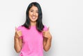 Beautiful asian young woman wearing casual pink t shirt success sign doing positive gesture with hand, thumbs up smiling and happy Royalty Free Stock Photo