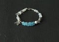 Beautiful asymmetrical designer bracelet made of natural stones and silver. Aquamarine, rock crystal, cacholong, larimar, Royalty Free Stock Photo