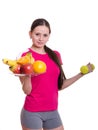 Beautiful athlete holding a plate of fruit and dumbbell Royalty Free Stock Photo