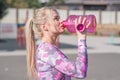 Beautiful and athletic blonde girl drinks water after jogging. Royalty Free Stock Photo