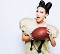 Beautiful, athletic brunette girl in American football uniform showing the ball having fun. Super bowl. Footy. Royalty Free Stock Photo
