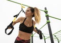 Beautiful athletic fitness woman exercising doing push ups suspension training with trx fitness straps in outdoor gym.Crossfit Royalty Free Stock Photo