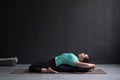 Beautiful athletic girl doing yoga supta virasana asana using bolster Royalty Free Stock Photo