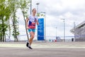 beautiful athletic girl runs at a city sports event, race, against the background of a new stadium