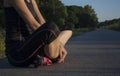 Beautiful athletic young adult woman is taking a break during outdoor exercising, sitting cross legged Royalty Free Stock Photo