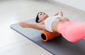 Beautiful athletic young woman in fashionable fit wear using foam roller in gym to workout to remove back pain, stretching and Royalty Free Stock Photo