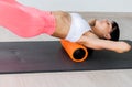 Beautiful athletic young woman in fashionable fit wear using foam roller in gym to workout to remove back pain, stretching and Royalty Free Stock Photo