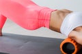 Beautiful athletic young woman in fashionable fit wear using foam roller in gym to workout to remove back pain, stretching and Royalty Free Stock Photo