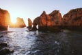 Atlantic ocean view horizon with sandy beach, rocks and waves at sunrise. Algarve, Portugal