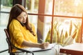 Beautiful Attractive Asian Business woman writing down requirement to book and talking with customer in smartphone