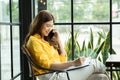 Beautiful Attractive Asian Business woman writing down requirement to book and talking with customer in smartphone