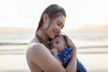 Beautiful Attractive Asian mom holding her baby newborn in hand and hugging baby sweet and lovely outdoor on the beach.Happy Royalty Free Stock Photo