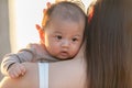 Beautiful Attractive Asian mom holding her baby newborn in hand and kissing on baby head sweet and lovely outdoor on the beach. Royalty Free Stock Photo