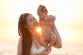 Beautiful Attractive Asian mom holding her baby newborn in hand and kissing on baby head sweet and lovely outdoor on the beach. Royalty Free Stock Photo