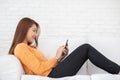 Beautiful Attractive Asian woman lying on white sofa using smartphone in living room smile and happiness Royalty Free Stock Photo
