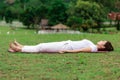 Beautiful Attractive Asian woman practice yoga Dead Body pose or Savasana pose lying on yoga mat with green grass for yoga Meditat Royalty Free Stock Photo